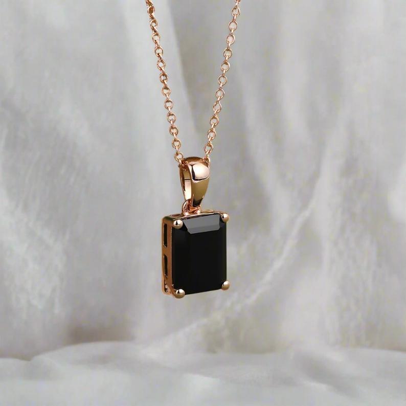 Emerald-cut black onyx pendant with 6x8mm centerpiece, featuring a 0.4-carat moissanite accent in a secure open basket setting, symbolizing strength and elegance